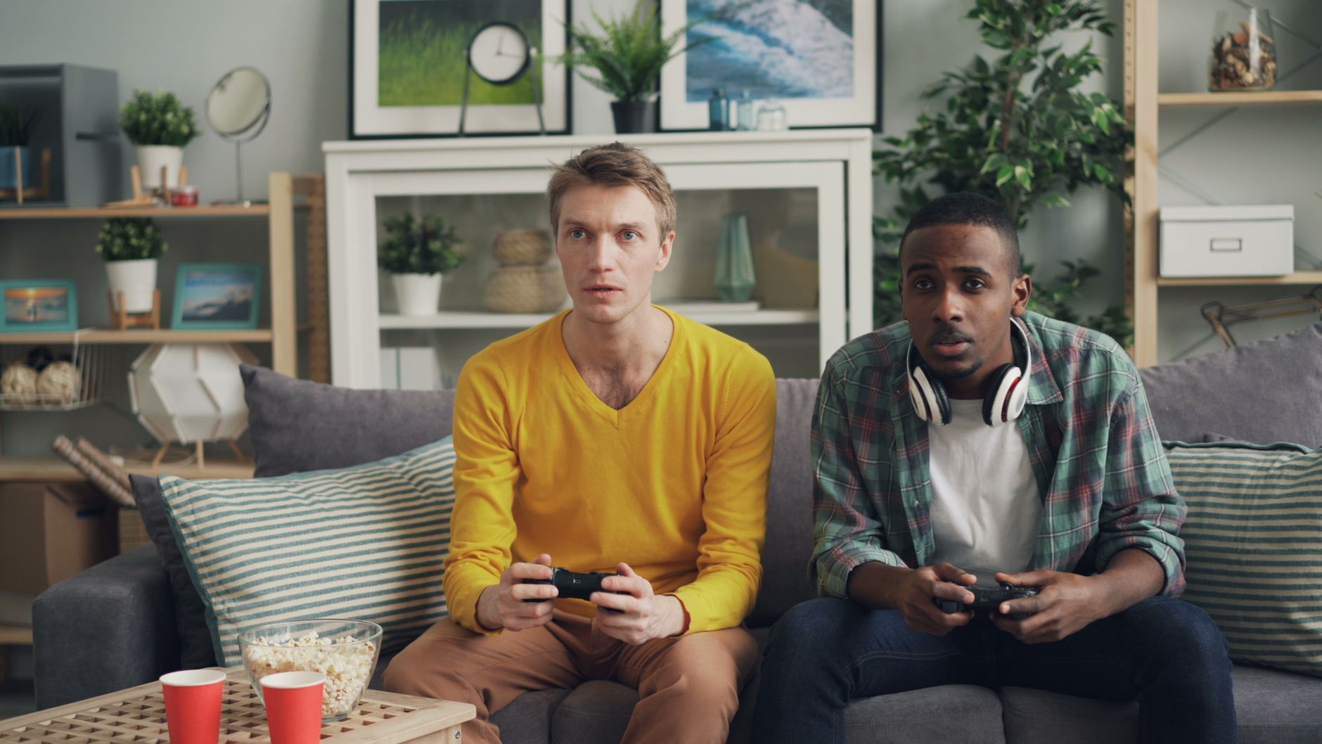 Two friends focus on gaming while relaxing on a couch in a modern living room. — Understanding the UFA656 Gaming and Betting